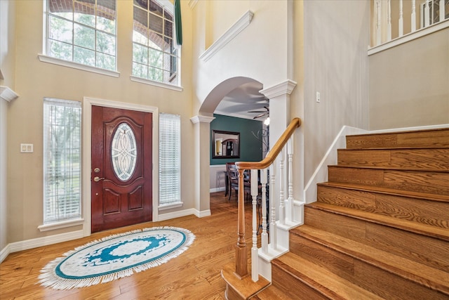 entryway with light hardwood / wood-style flooring, decorative columns, ceiling fan, and a high ceiling