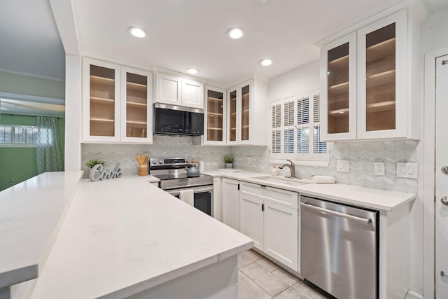 kitchen with white cabinetry, appliances with stainless steel finishes, light tile patterned flooring, and backsplash