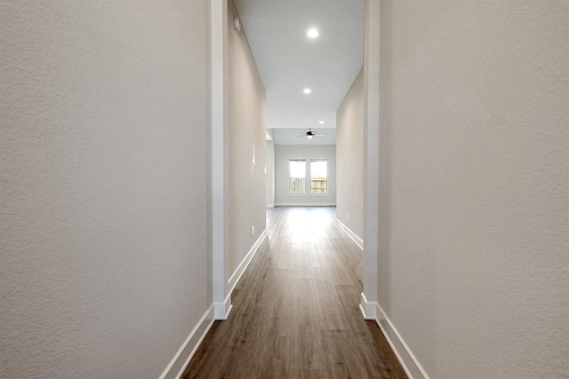 hall featuring dark wood-style floors, baseboards, and a textured wall