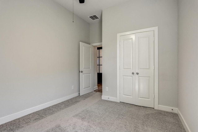 unfurnished bedroom featuring carpet flooring, visible vents, baseboards, and a closet