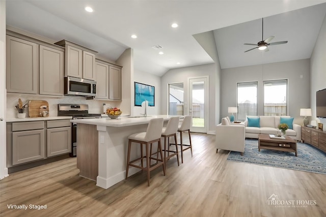 kitchen with appliances with stainless steel finishes, open floor plan, gray cabinets, and vaulted ceiling