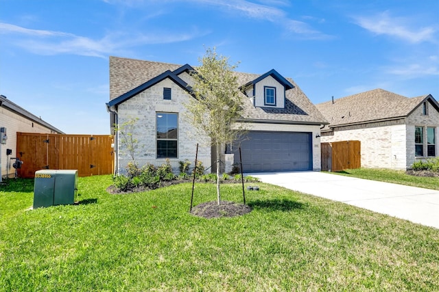 french country home featuring a gate, fence, an attached garage, concrete driveway, and a front lawn