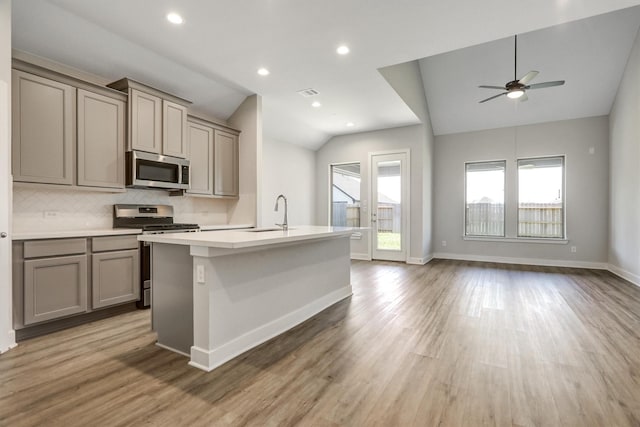 kitchen with lofted ceiling, tasteful backsplash, appliances with stainless steel finishes, and gray cabinets