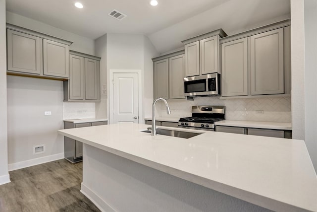 kitchen featuring visible vents, decorative backsplash, gray cabinets, appliances with stainless steel finishes, and a sink