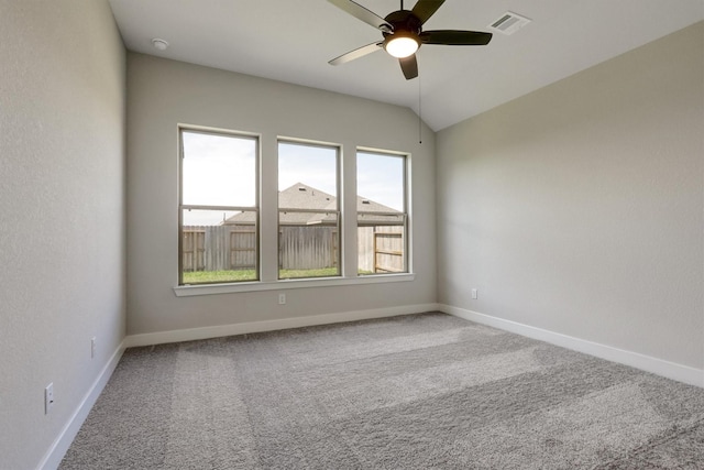 carpeted empty room featuring visible vents, baseboards, lofted ceiling, and ceiling fan