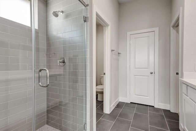 bathroom featuring toilet, a shower stall, tile patterned flooring, baseboards, and vanity