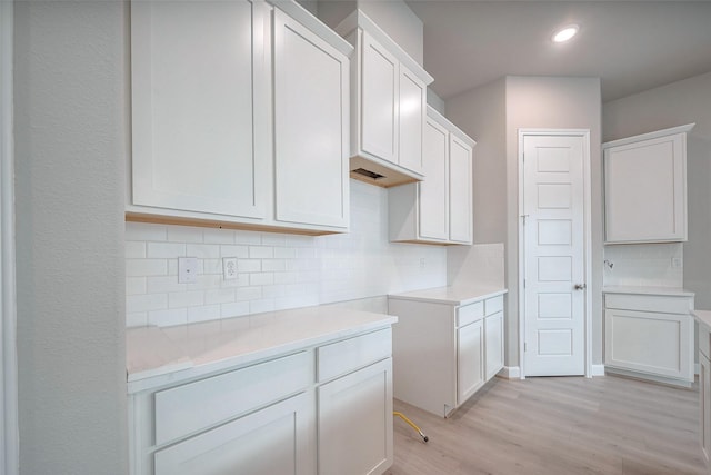 kitchen featuring tasteful backsplash, light countertops, light wood-style floors, white cabinetry, and recessed lighting