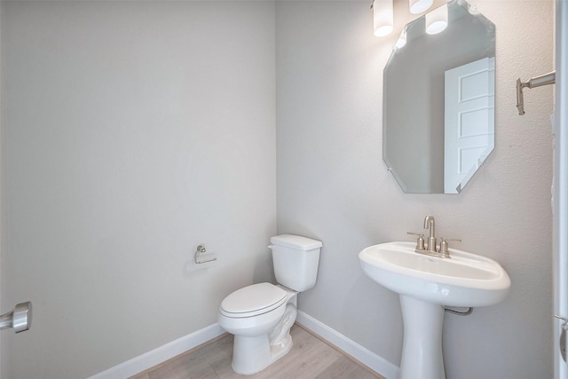 half bath featuring toilet, baseboards, and wood finished floors