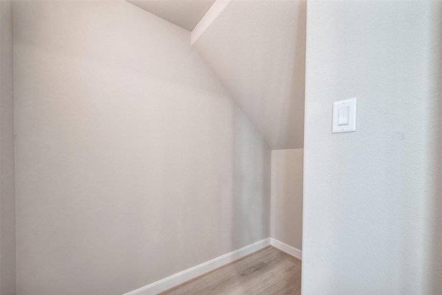 additional living space with light wood-type flooring, vaulted ceiling, and baseboards