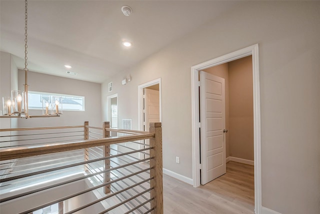 hallway with baseboards, an inviting chandelier, an upstairs landing, light wood-type flooring, and recessed lighting