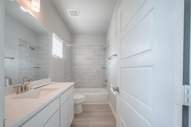 bathroom featuring shower / bathtub combination, visible vents, toilet, vanity, and wood finished floors