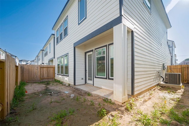 view of side of home with a patio area, a fenced backyard, and central air condition unit