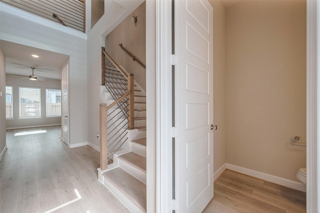 stairway featuring a ceiling fan, baseboards, and wood finished floors