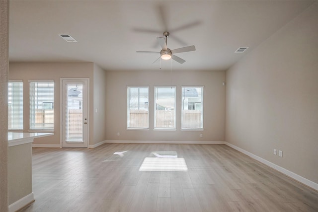 empty room featuring light wood-type flooring, visible vents, and baseboards