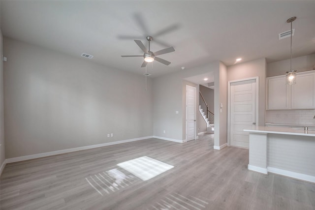 unfurnished living room featuring light wood-type flooring, baseboards, visible vents, and ceiling fan