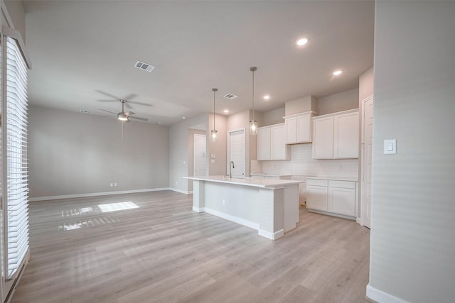 kitchen with visible vents, backsplash, a ceiling fan, a sink, and light wood-type flooring