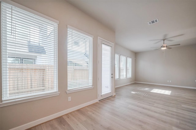 spare room featuring baseboards, ceiling fan, visible vents, and light wood-style floors