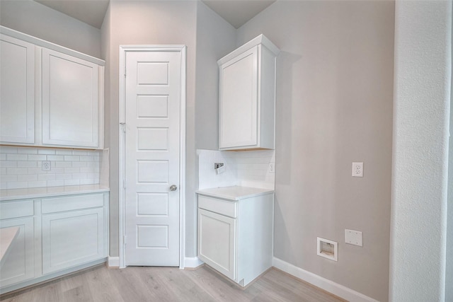 clothes washing area with light wood-type flooring, laundry area, and baseboards