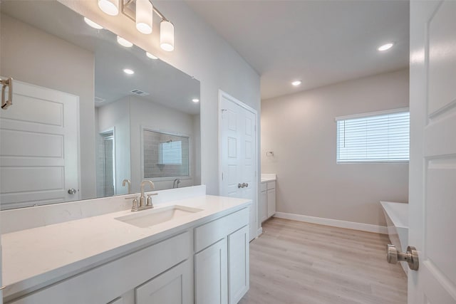 bathroom featuring wood finished floors, vanity, visible vents, baseboards, and walk in shower