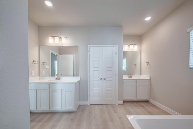 full bath featuring recessed lighting, two vanities, wood finished floors, and baseboards