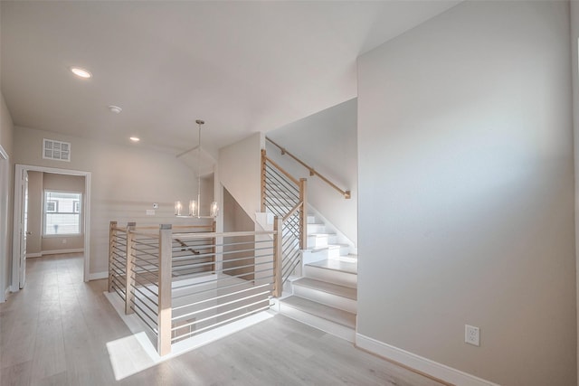 staircase featuring wood finished floors, visible vents, and baseboards