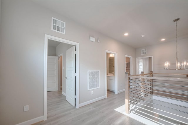 hallway featuring light wood-type flooring, an upstairs landing, and visible vents