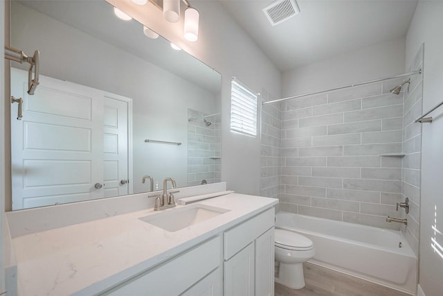 bathroom featuring visible vents, toilet, shower / tub combination, wood finished floors, and vanity