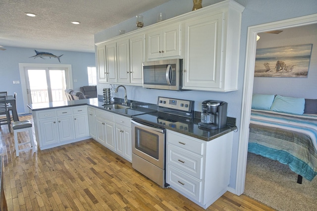 kitchen featuring sink, kitchen peninsula, white cabinets, and appliances with stainless steel finishes