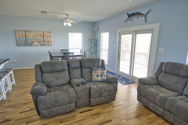 living room with hardwood / wood-style floors, a textured ceiling, and ceiling fan