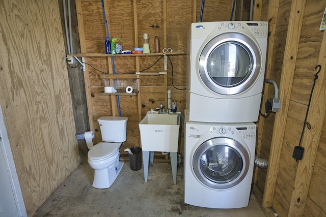 washroom with stacked washer / drying machine and sink