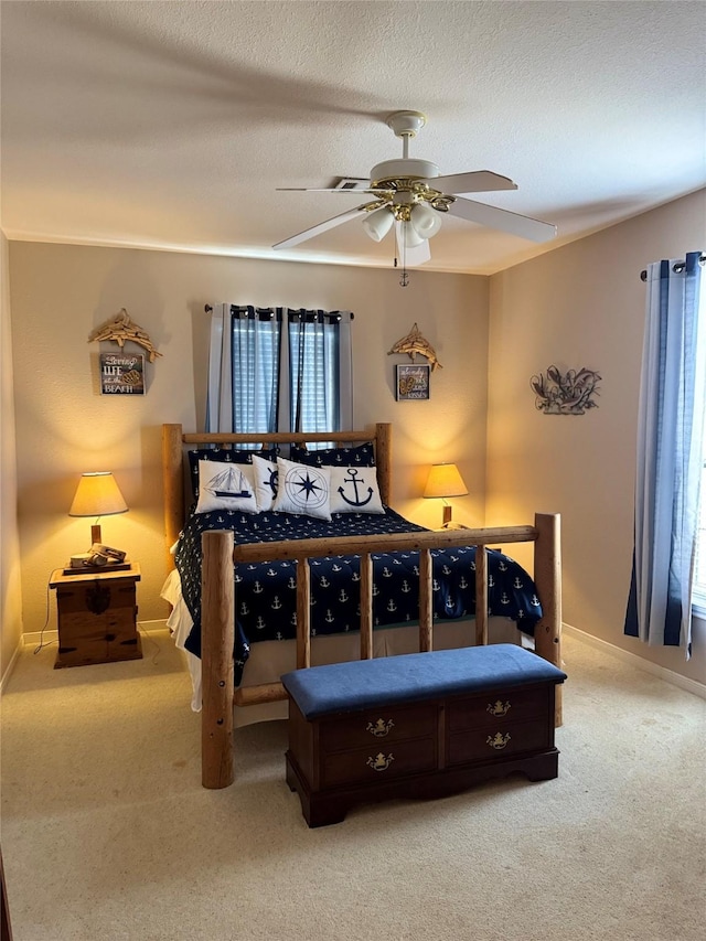 bedroom with ceiling fan, carpet floors, and a textured ceiling