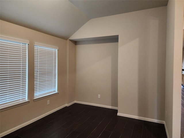 empty room featuring vaulted ceiling and dark hardwood / wood-style floors