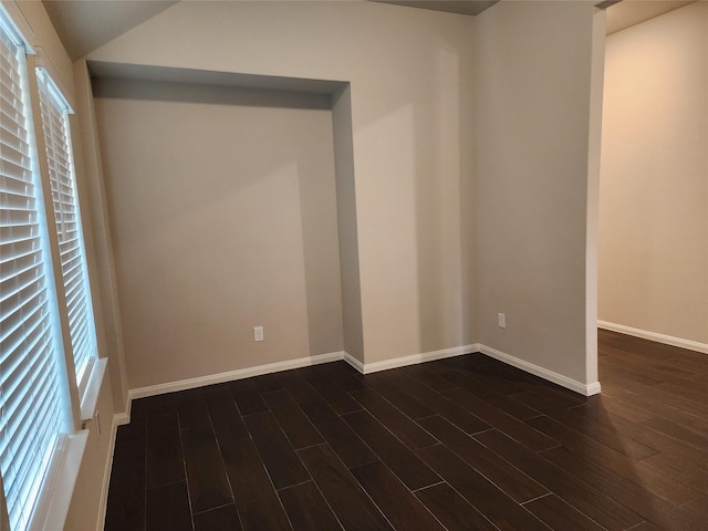 spare room with dark hardwood / wood-style flooring, vaulted ceiling, and a wealth of natural light