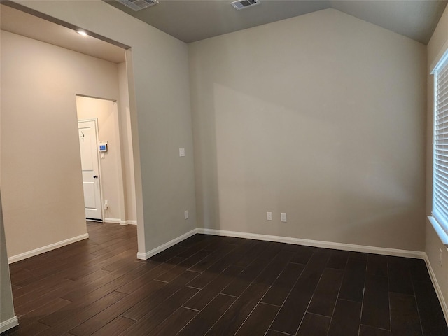 spare room featuring vaulted ceiling and dark wood-type flooring