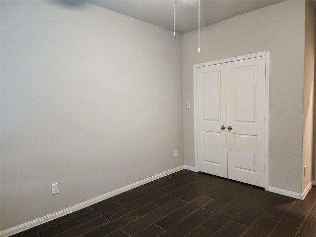 unfurnished bedroom with dark wood-type flooring and a closet