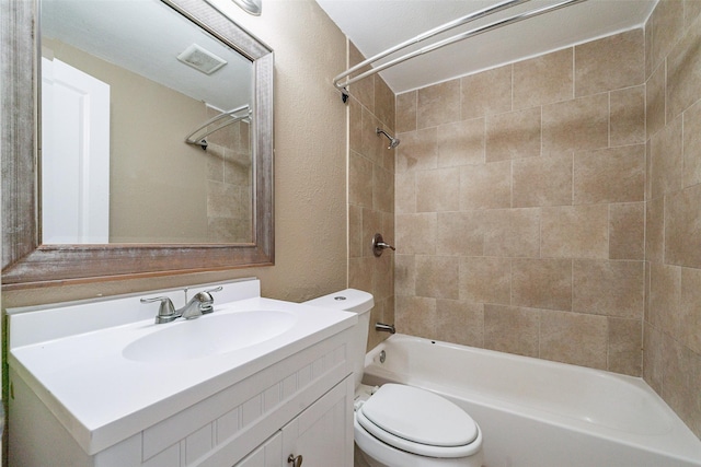 full bathroom featuring tiled shower / bath, vanity, and toilet