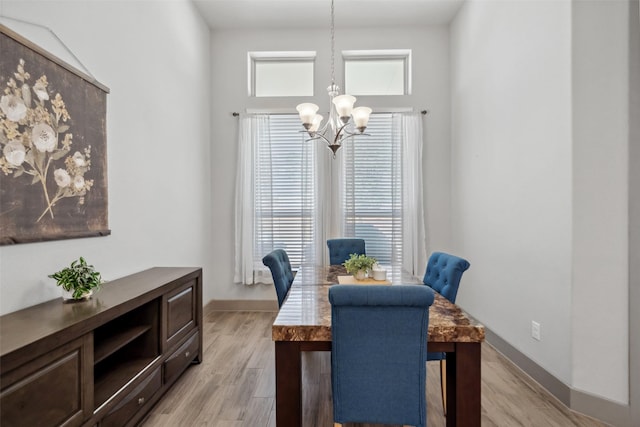 dining area featuring an inviting chandelier, baseboards, and light wood-type flooring