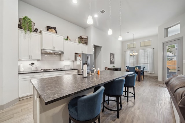 kitchen with dark countertops, tasteful backsplash, stainless steel fridge with ice dispenser, a kitchen breakfast bar, and gas cooktop