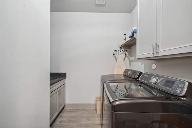 laundry area with cabinets, washing machine and clothes dryer, and light wood-type flooring