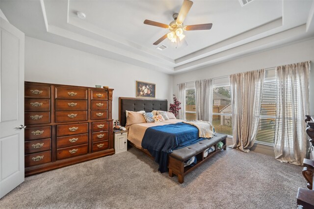 carpeted bedroom with a tray ceiling and ceiling fan