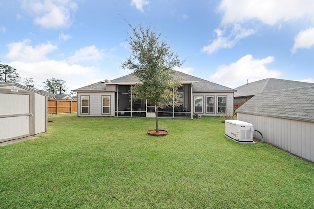 back of property featuring fence, a shed, a yard, an outdoor structure, and a sunroom