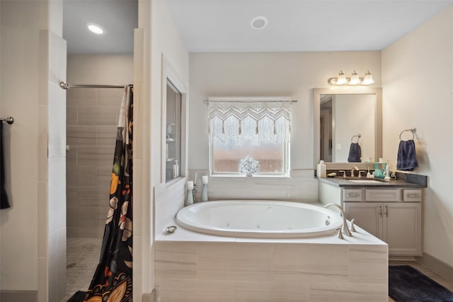 bathroom featuring tiled shower, a jetted tub, and vanity