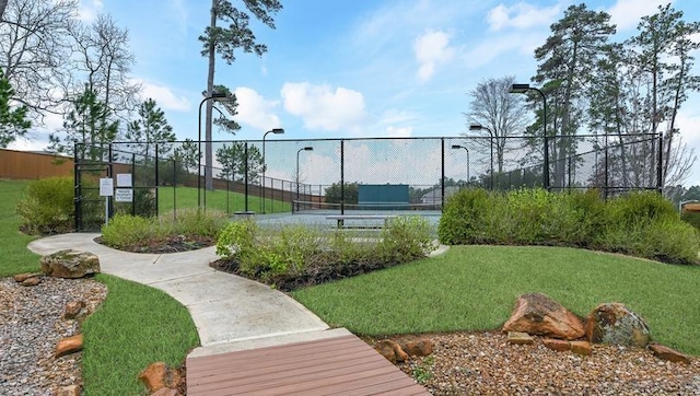 view of sport court with a yard and fence