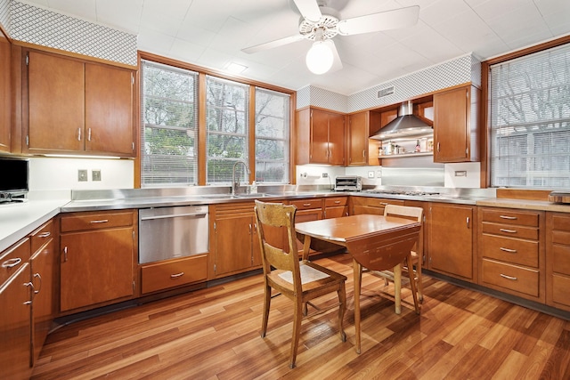 kitchen featuring ceiling fan, sink, light hardwood / wood-style flooring, and wall chimney range hood