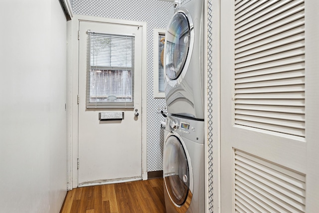 laundry room featuring stacked washer and dryer and wood-type flooring