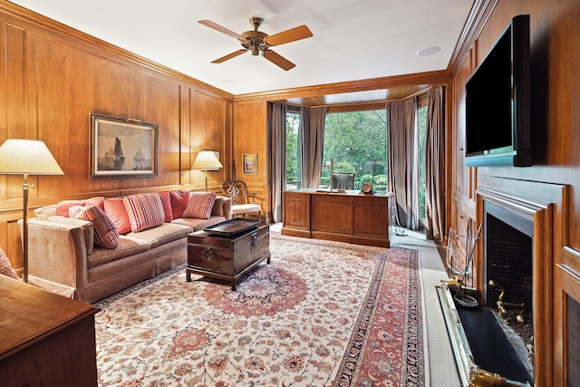 living room with crown molding, ceiling fan, and wood walls