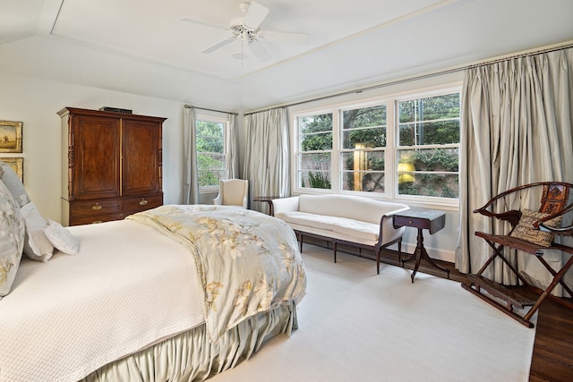 bedroom with lofted ceiling, hardwood / wood-style flooring, a raised ceiling, and ceiling fan