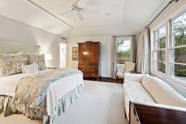 bedroom featuring a raised ceiling, vaulted ceiling, dark wood-type flooring, and ceiling fan