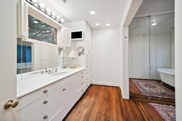 bathroom with a bath, vanity, and hardwood / wood-style floors