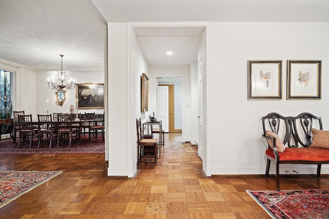 hall featuring an inviting chandelier, crown molding, and parquet flooring